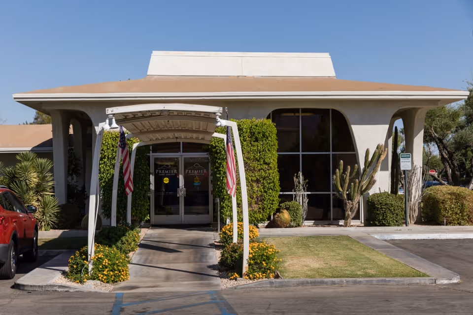 Premier Care Center for Palm Springs entrance with glass doors, archway, flags, and desert landscaping.