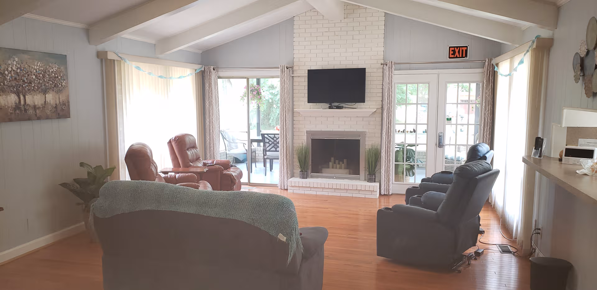 Cozy living room with a fireplace, mounted TV, recliners, and sliding doors.