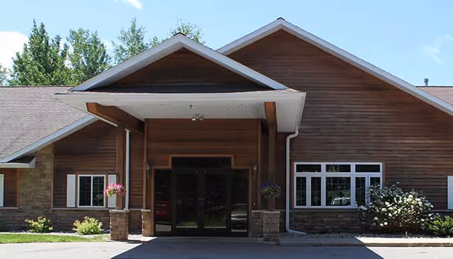 North Crest Assisted Living entrance with wooden facade, glass doors, and hanging flower pots.