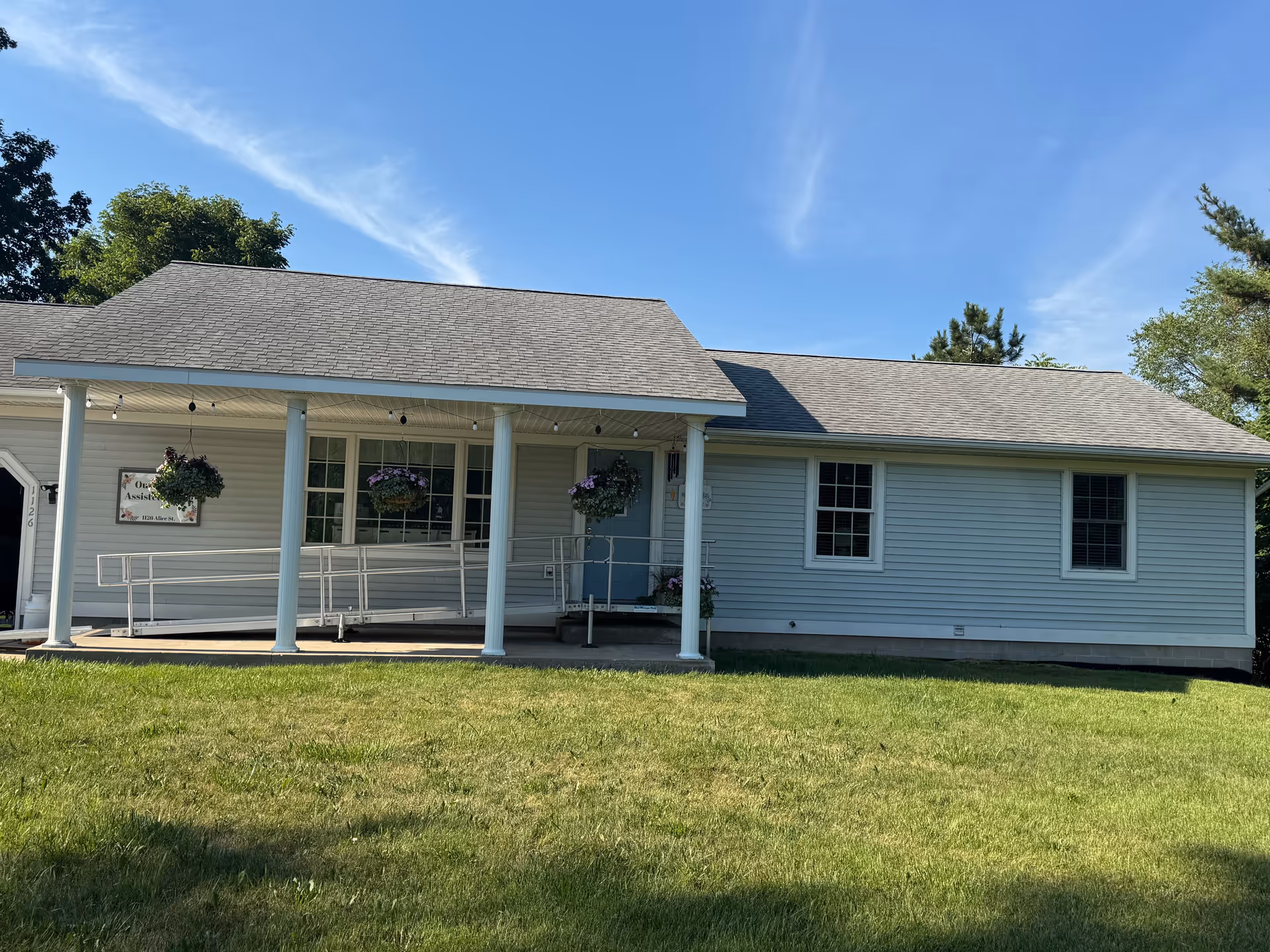 Front view of Our Family Assisted Living facility with a covered porch and hanging planters.