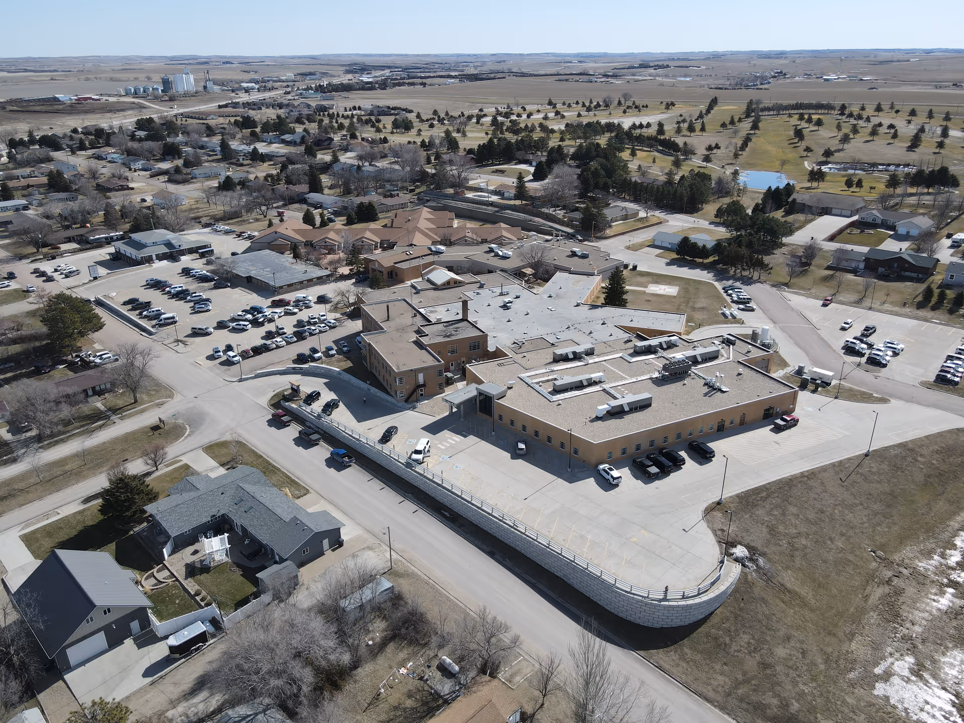Aerial view of a hospital campus with a large beige building and surrounding parking.