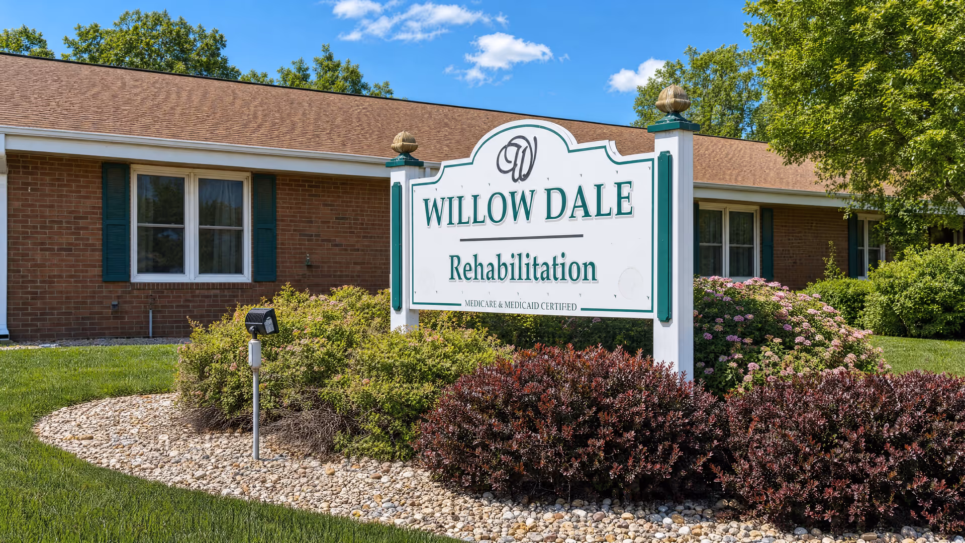 Front view of Willow Dale Rehabilitation sign with brick building and landscaping.