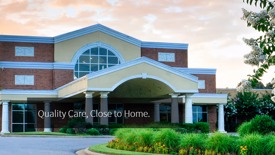 Front exterior of a brick medical center with arches and landscaped greenery.