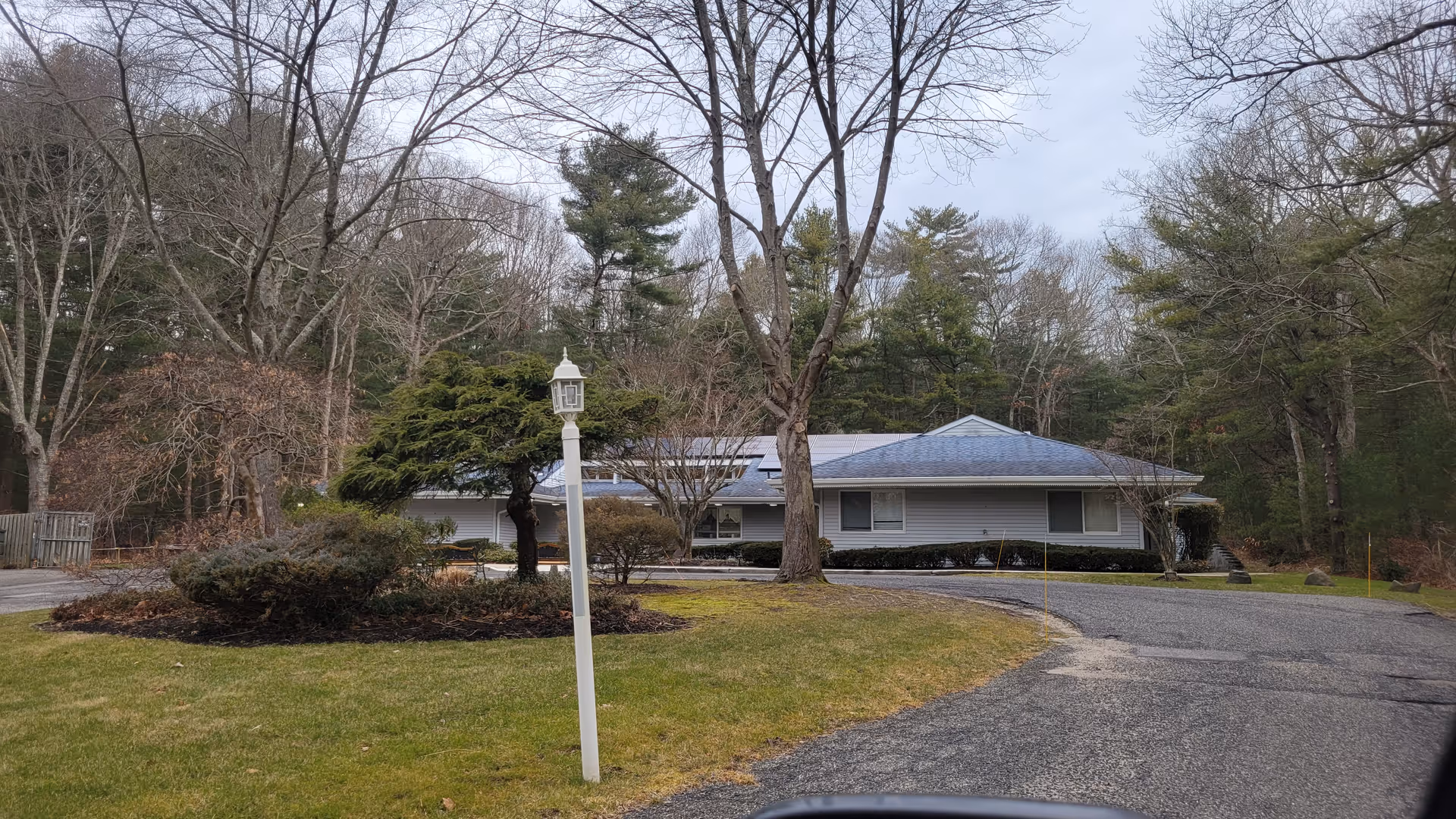 Exterior view of a single-story senior living facility with a curved driveway and trees.