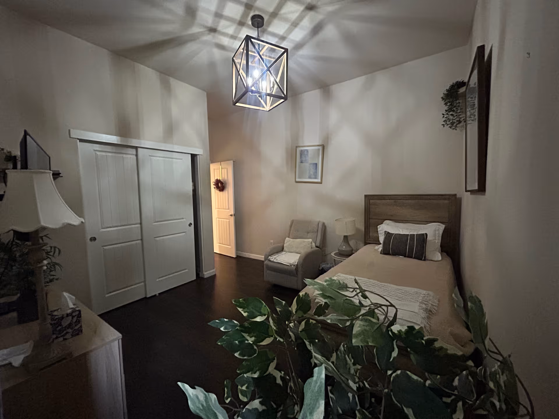 Bedroom in Rose Garden Home Care with bed, chair, and greenery.