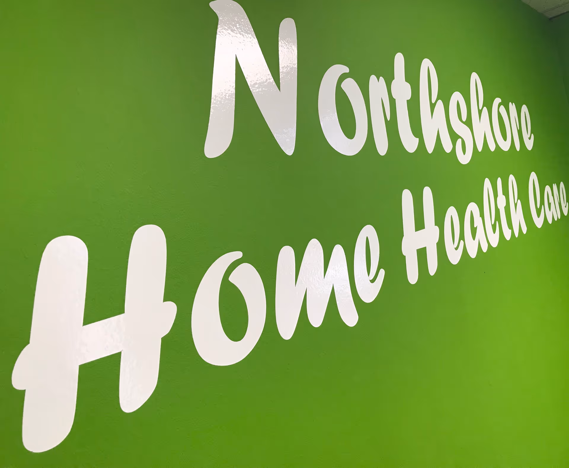Bright green interior wall with a large white NorthShore Home Health Care sign.