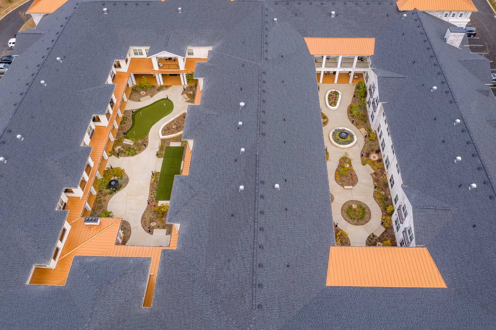 Aerial view of a U-shaped senior living campus with landscaped courtyards and winding paths.