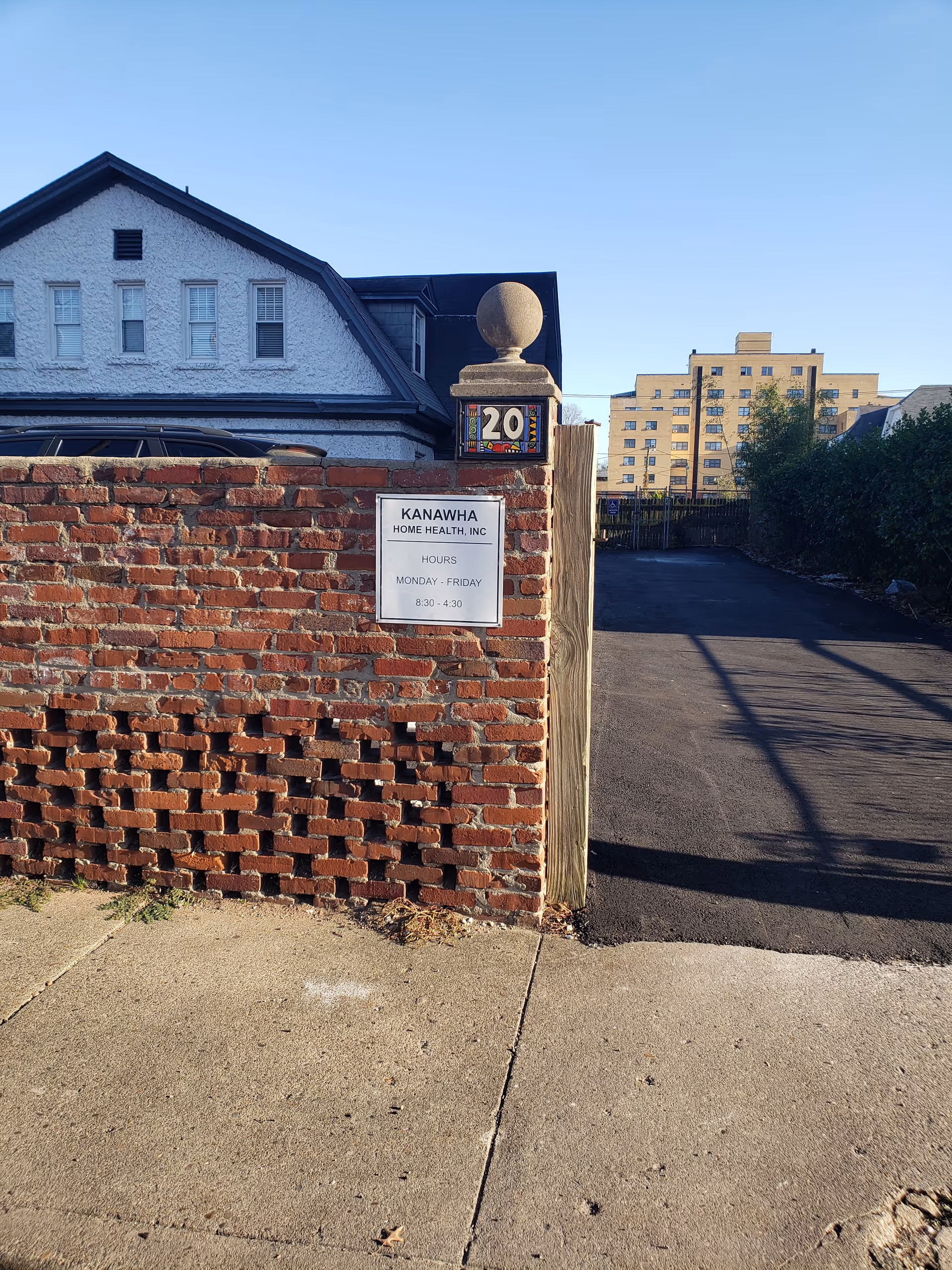 Exterior view of brick wall gate with Kanawha Home Health, Inc. sign and driveway.