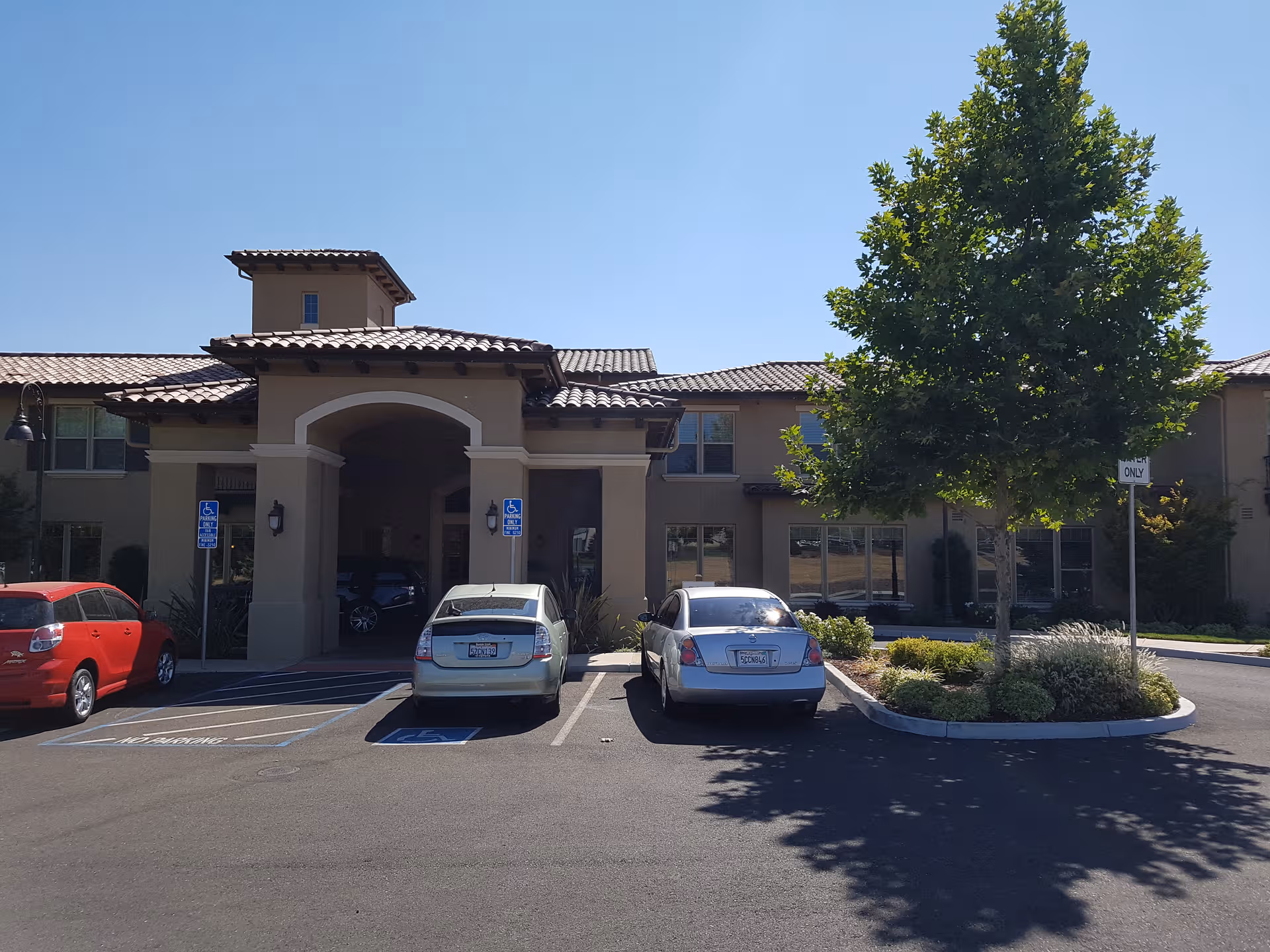 Front view of Oakmont of Folsom senior living center with cars in the parking lot.