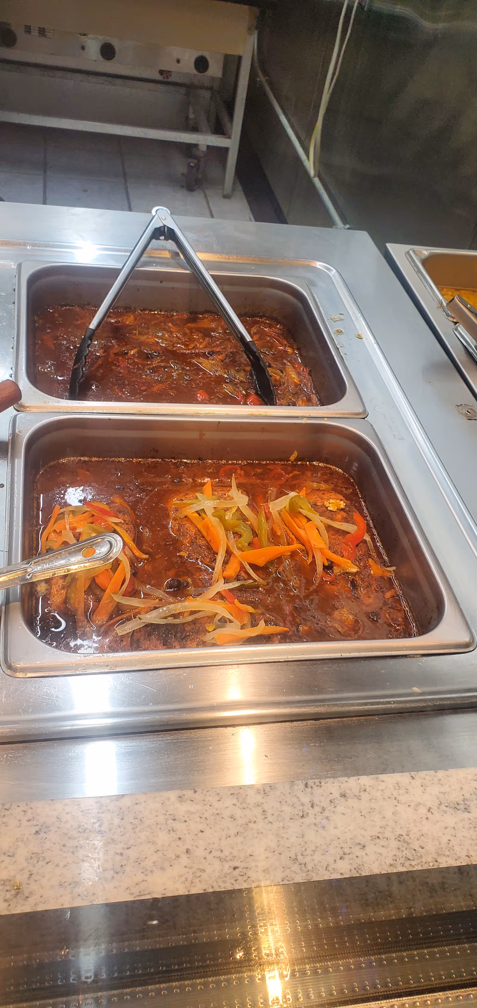 Stainless steel steam table with two chafing dish trays of stew and vegetables.