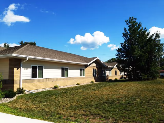 Single-story Care Partners Weston facility exterior with brick, beige siding, and a green lawn.