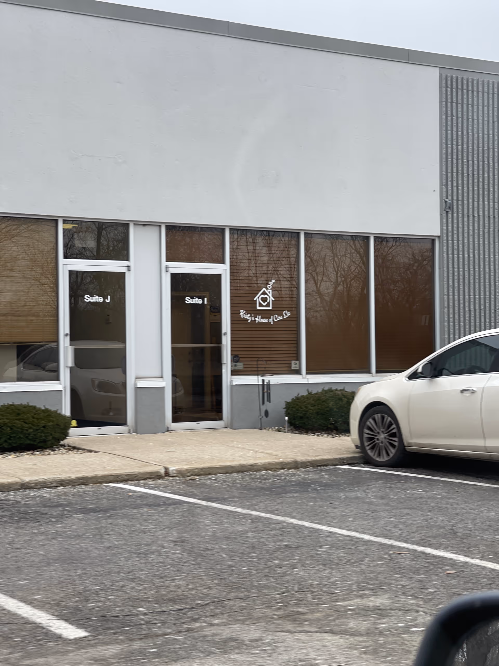 Outside view of Kristy's House of Care entrance with suite doors and a parked car.