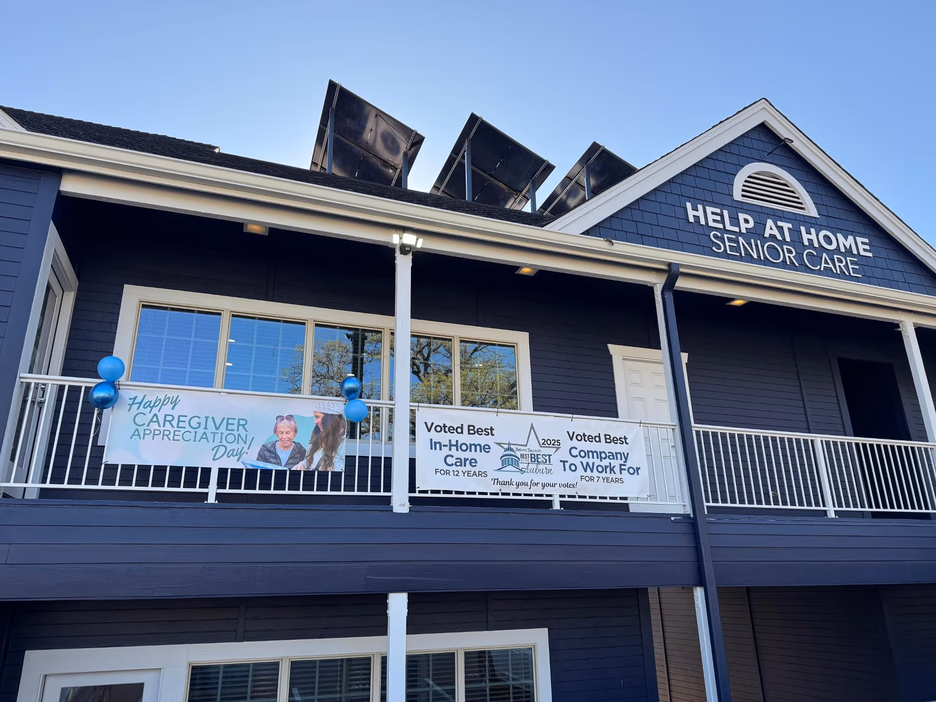 Blue senior care facility exterior with banners and the name Help at Home Senior Care.