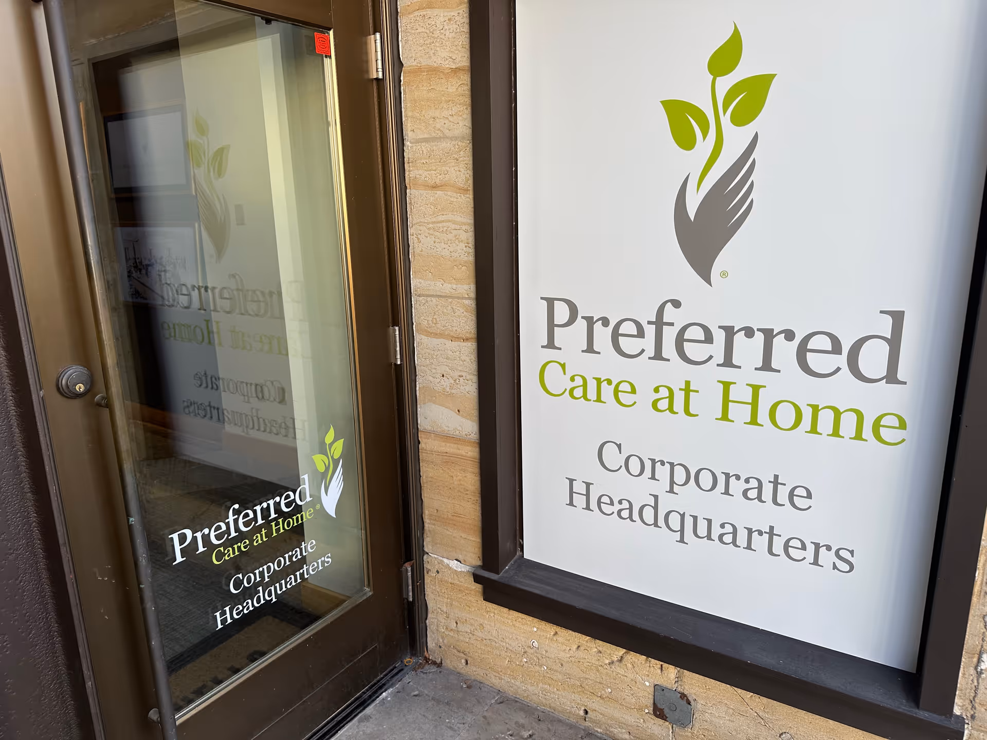 Entrance of Preferred Care at Home Corporate Headquarters with glass door and large sign.