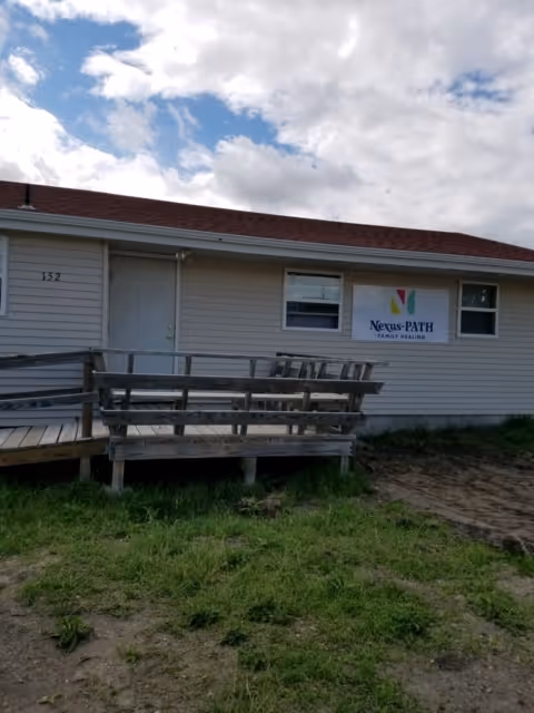 One-story Nexus-PATH Family Healing building exterior with a wooden ramp and sign.