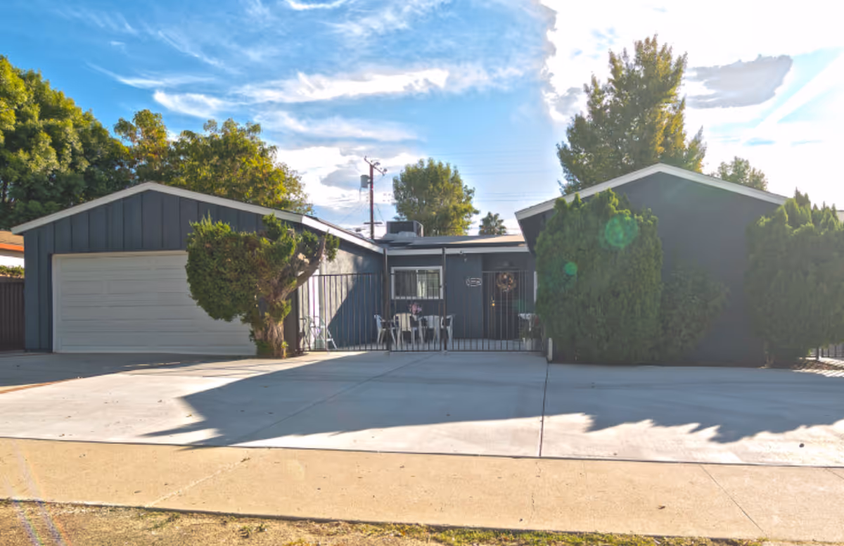 Exterior view of Monroe Home facility with garage, trees, and small patio seating.