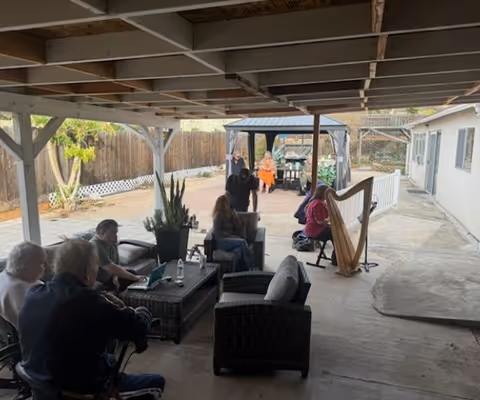 Residents socialize on a covered outdoor patio with seating and a harp.