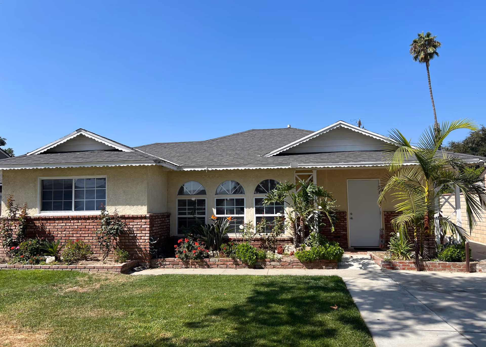 Front view of a single-story beige home with brick accents and landscaped yard.