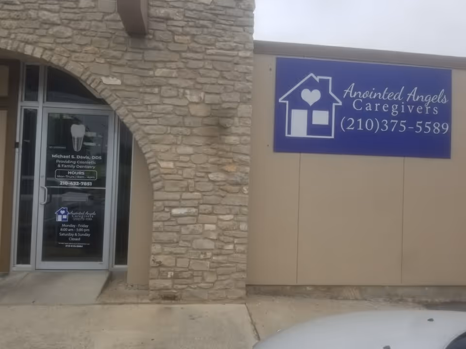 Beige building exterior with a blue Anointed Angels Caregivers sign on the wall.