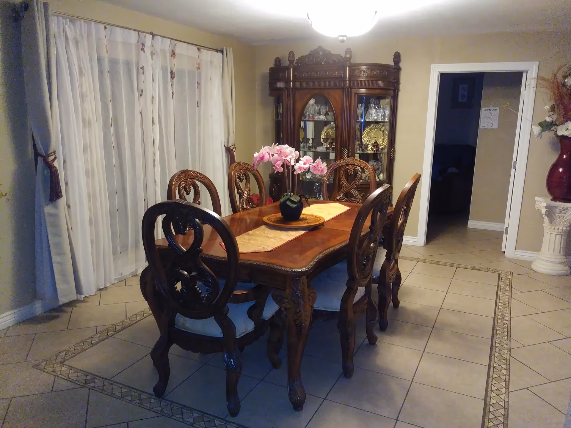 Elegant wooden dining table with six chairs and a china cabinet in a formal dining room.