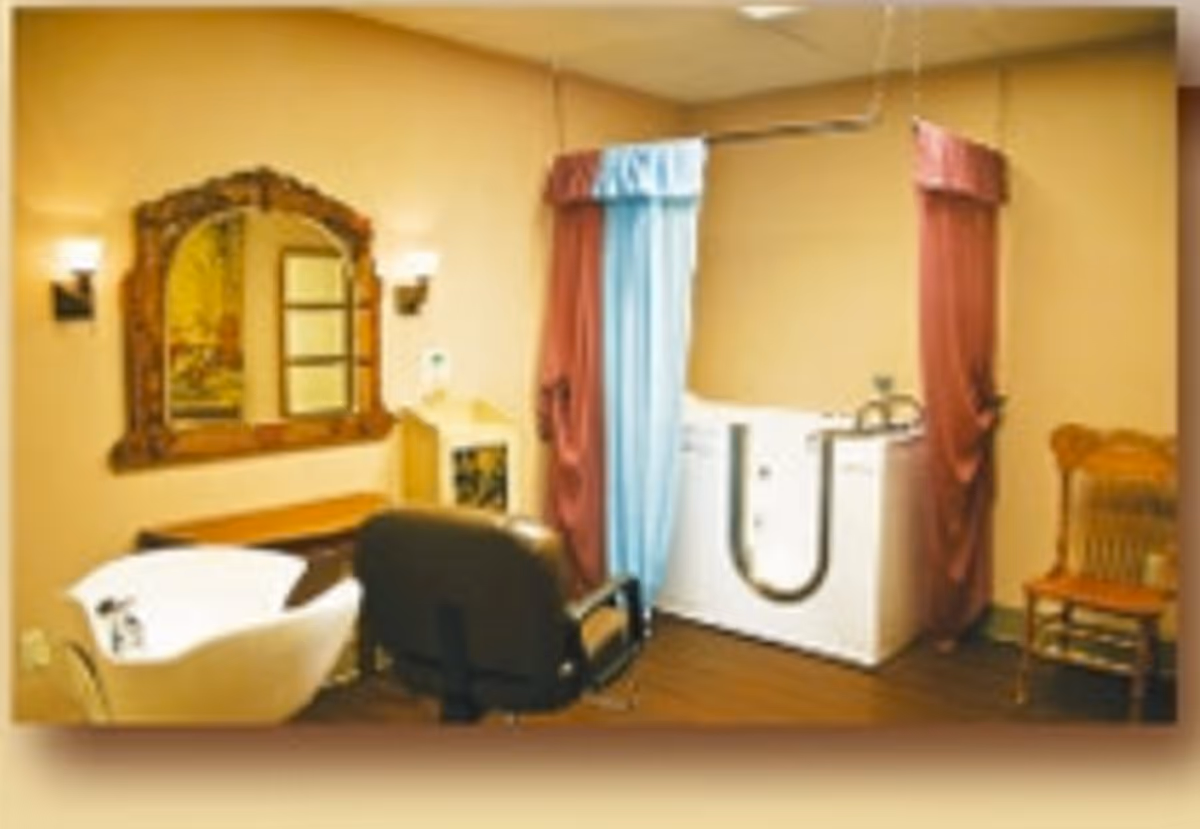 Warm-toned interior with a curtained tub area and seating in a senior living room.