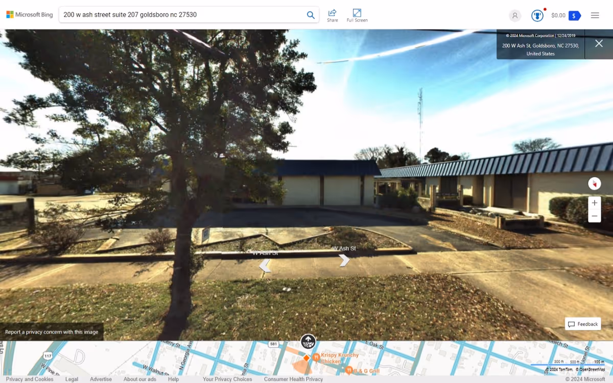 Exterior view of Encouraging Hearts LLC facility with a tree and parking lot