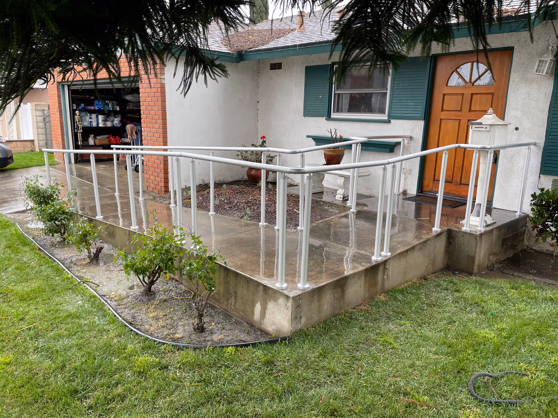 Exterior view of a house entrance with a metal ramp and handrails.