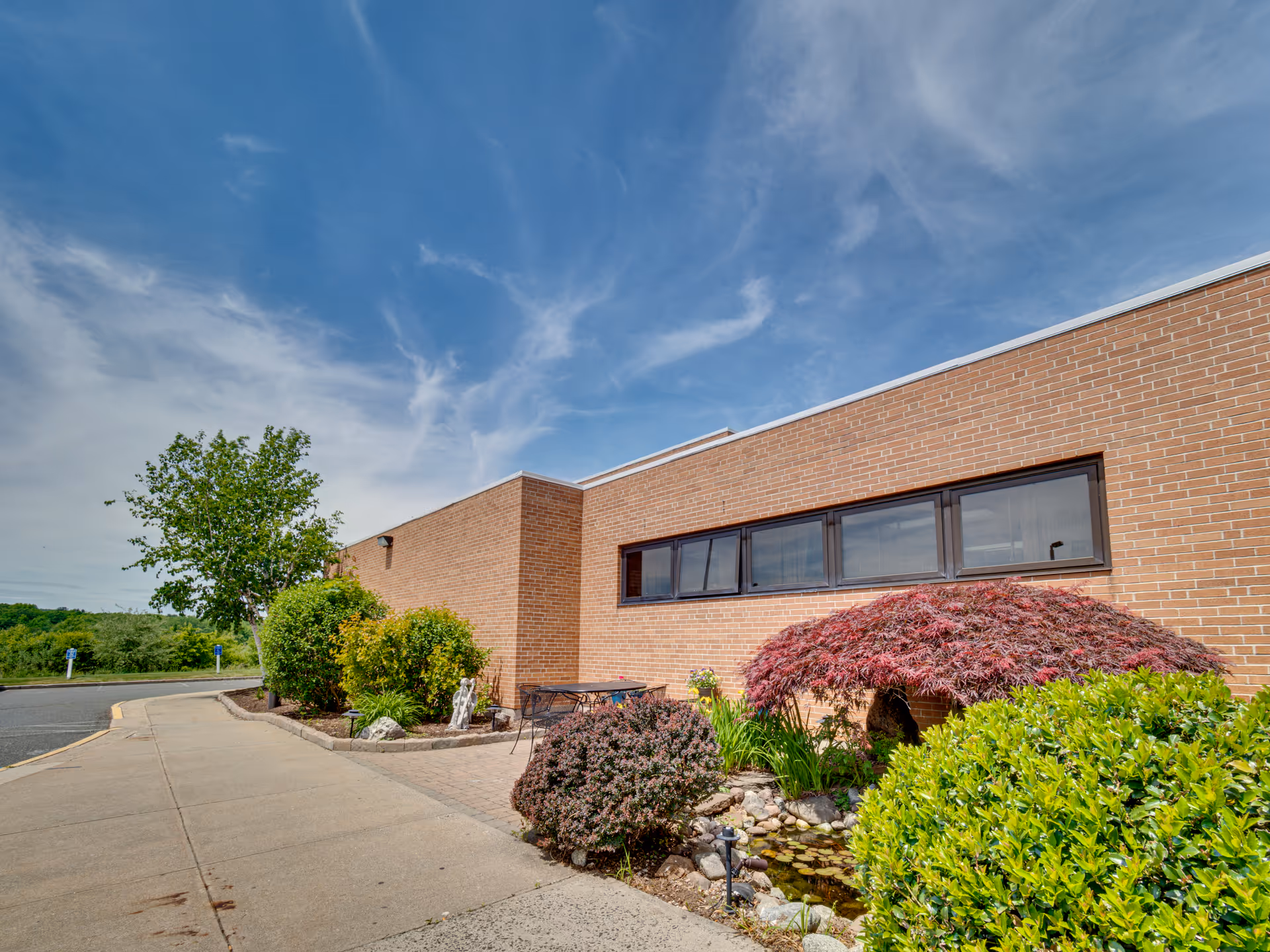 Brick MissionCare at Holyoke building exterior with windows, landscaped garden, and blue sky.