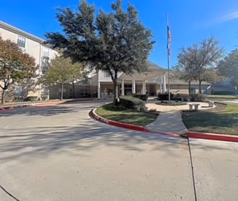 Exterior view of The Waterford at Fort Worth showing entrance with flagpole and landscaping.