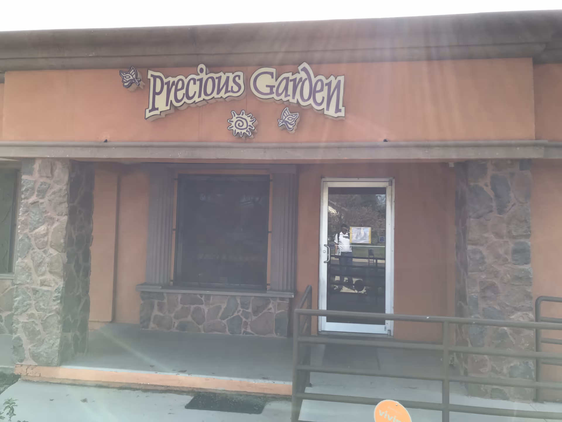 Exterior view of Precious Garden Primary Care entrance with stone facade and ramp.