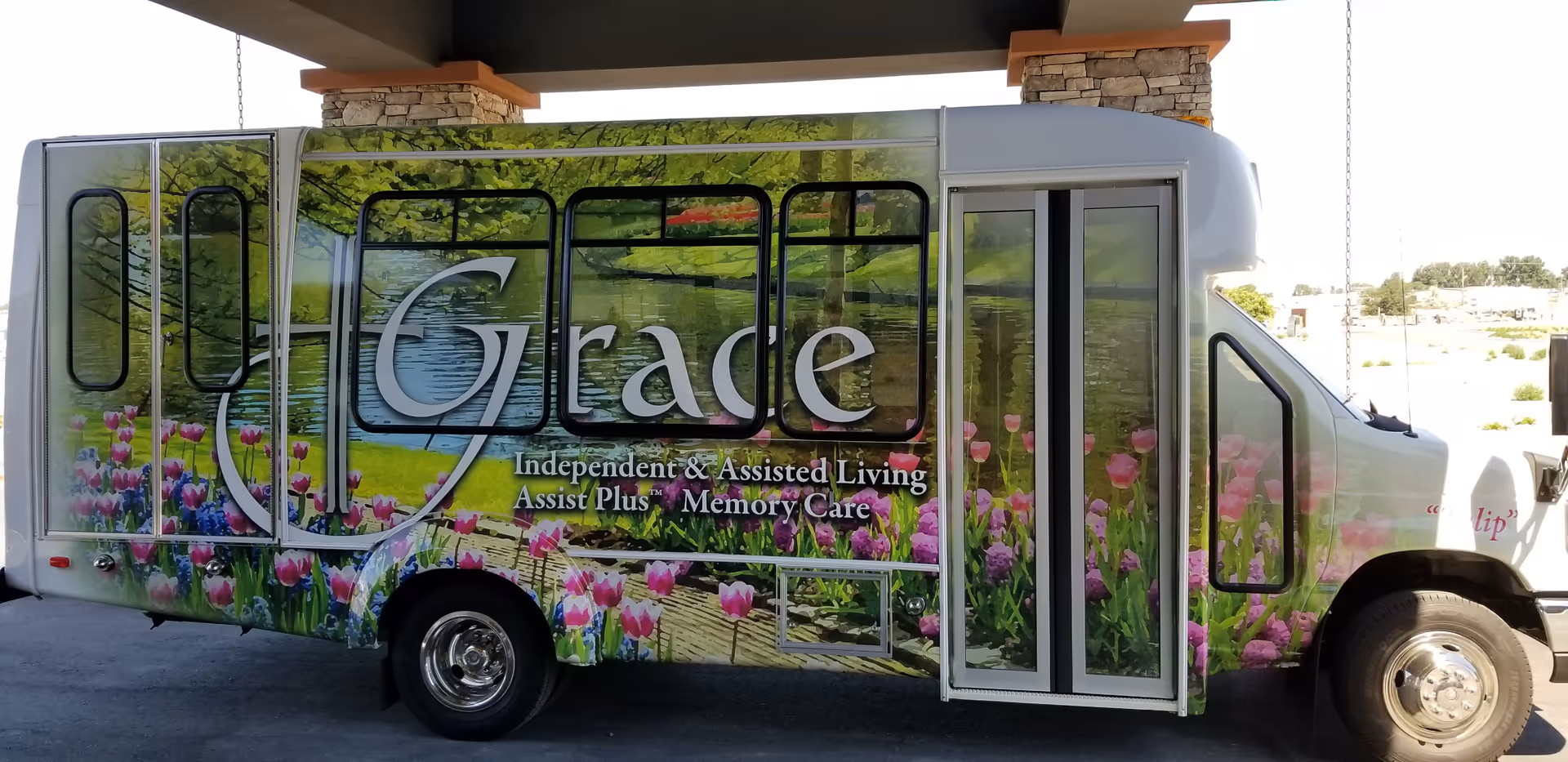 A Grace Independent and Assisted Living bus with tulip graphics parked outdoors.