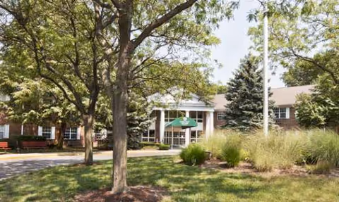 Exterior view of Oakleaf Village of Toledo with brick building, green awning, and trees.