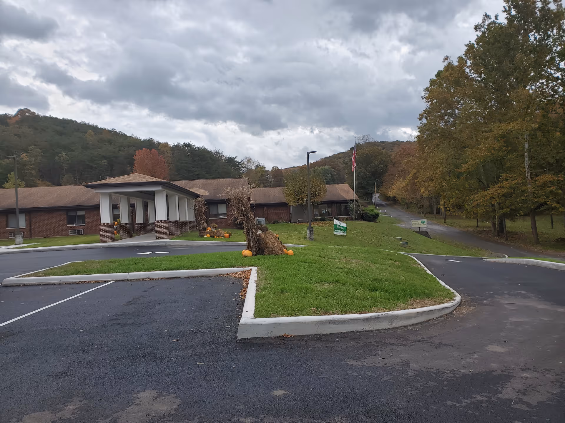 Exterior view of Summers Healthcare Center with brick building, front entrance, parking, and pumpkins.