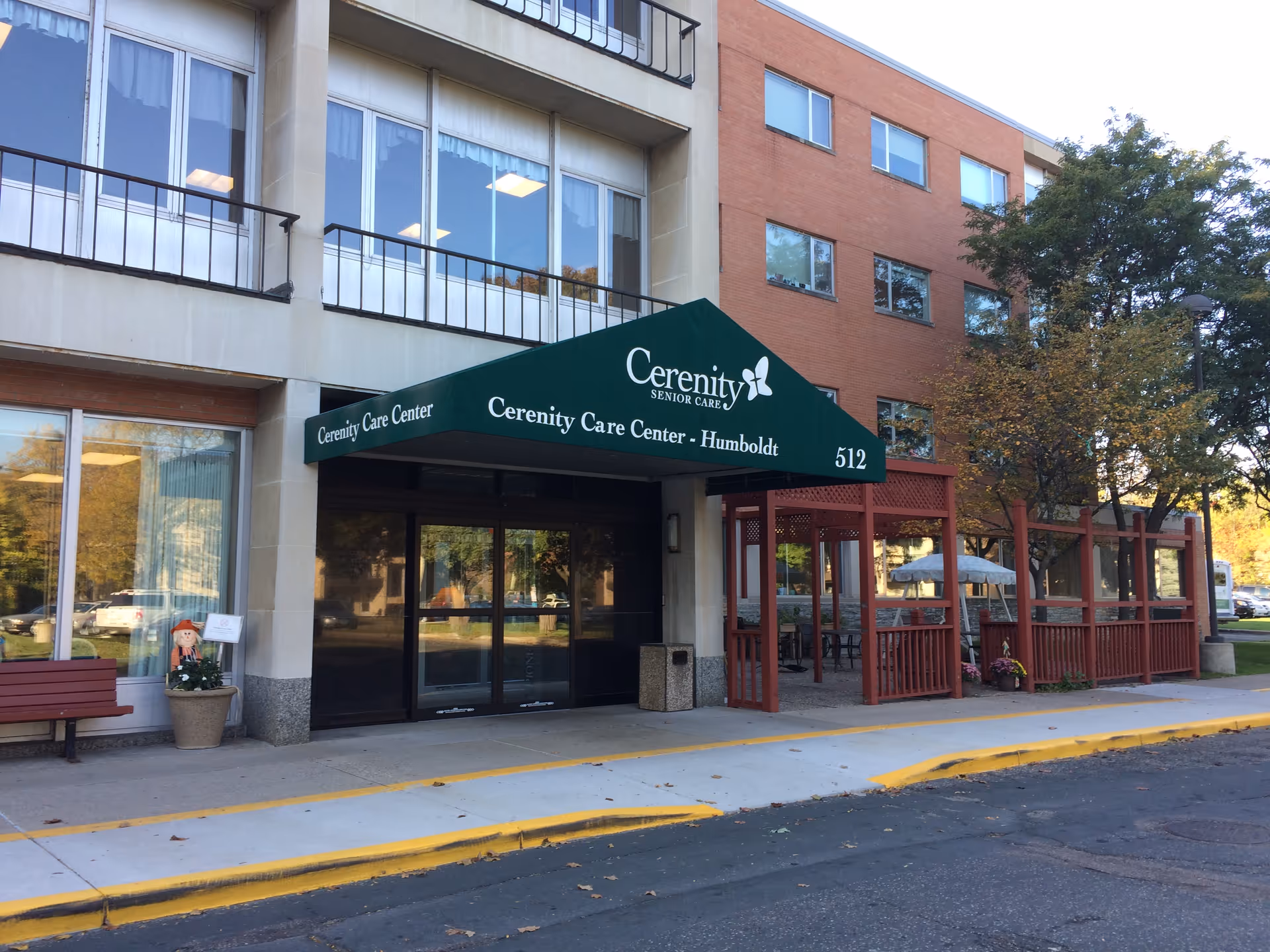 Exterior view of Cerenity Residence on Humboldt with green awning over entrance and outdoor seating.