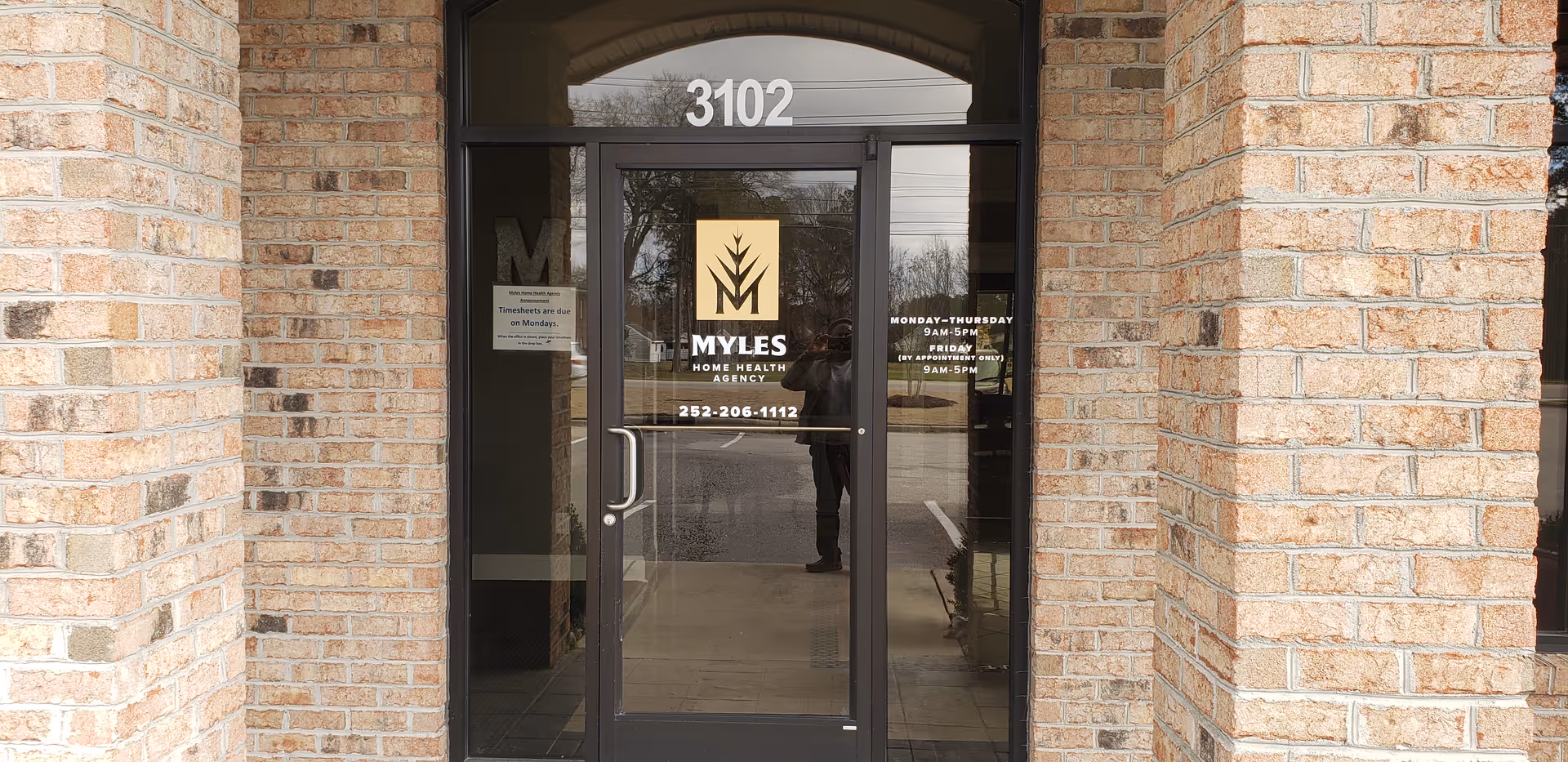 Brick exterior entrance with glass doors displaying Myles Home Health Agency branding and 3102.