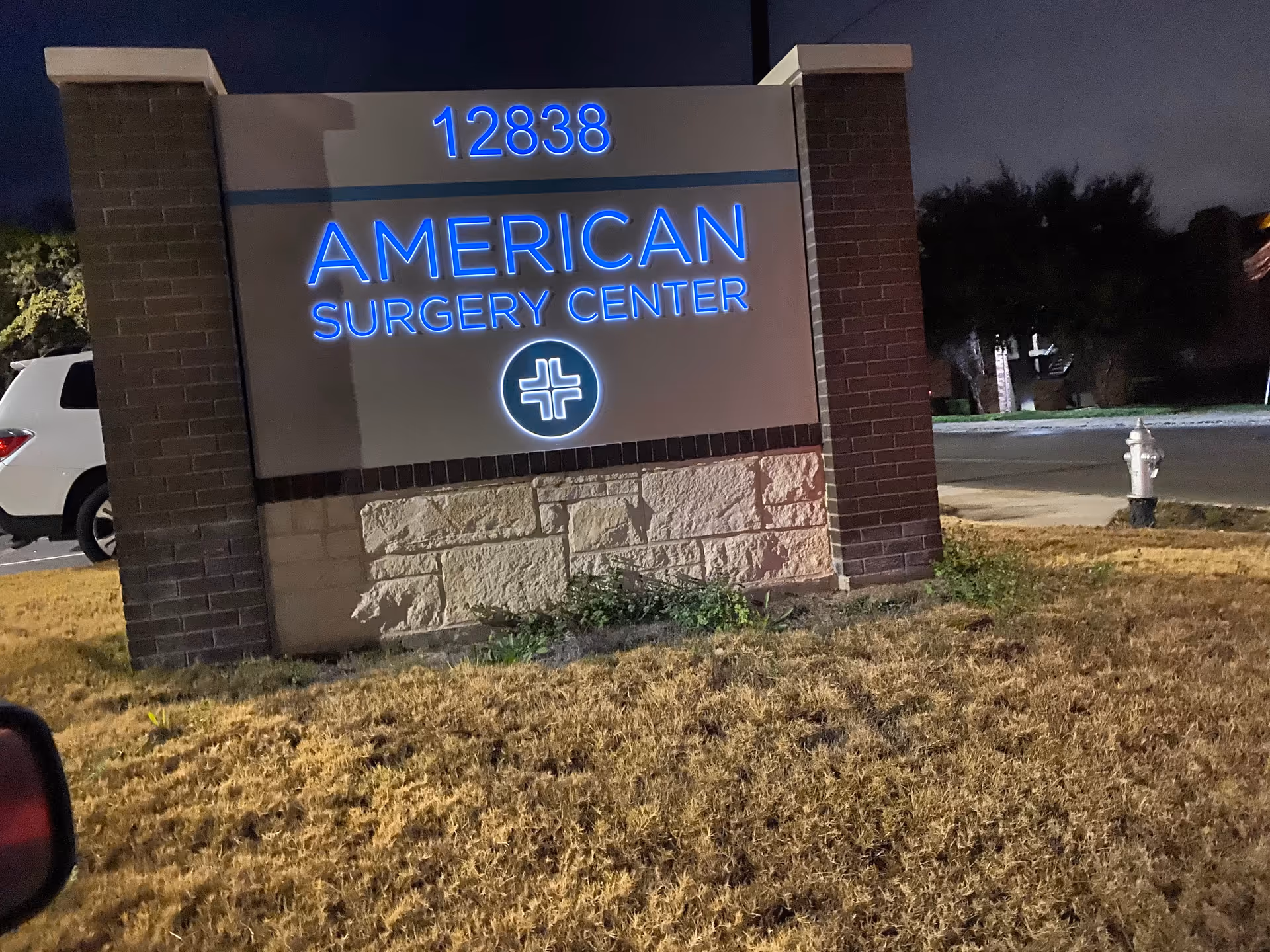 Night view of illuminated American Surgery Center entrance sign with address 12838