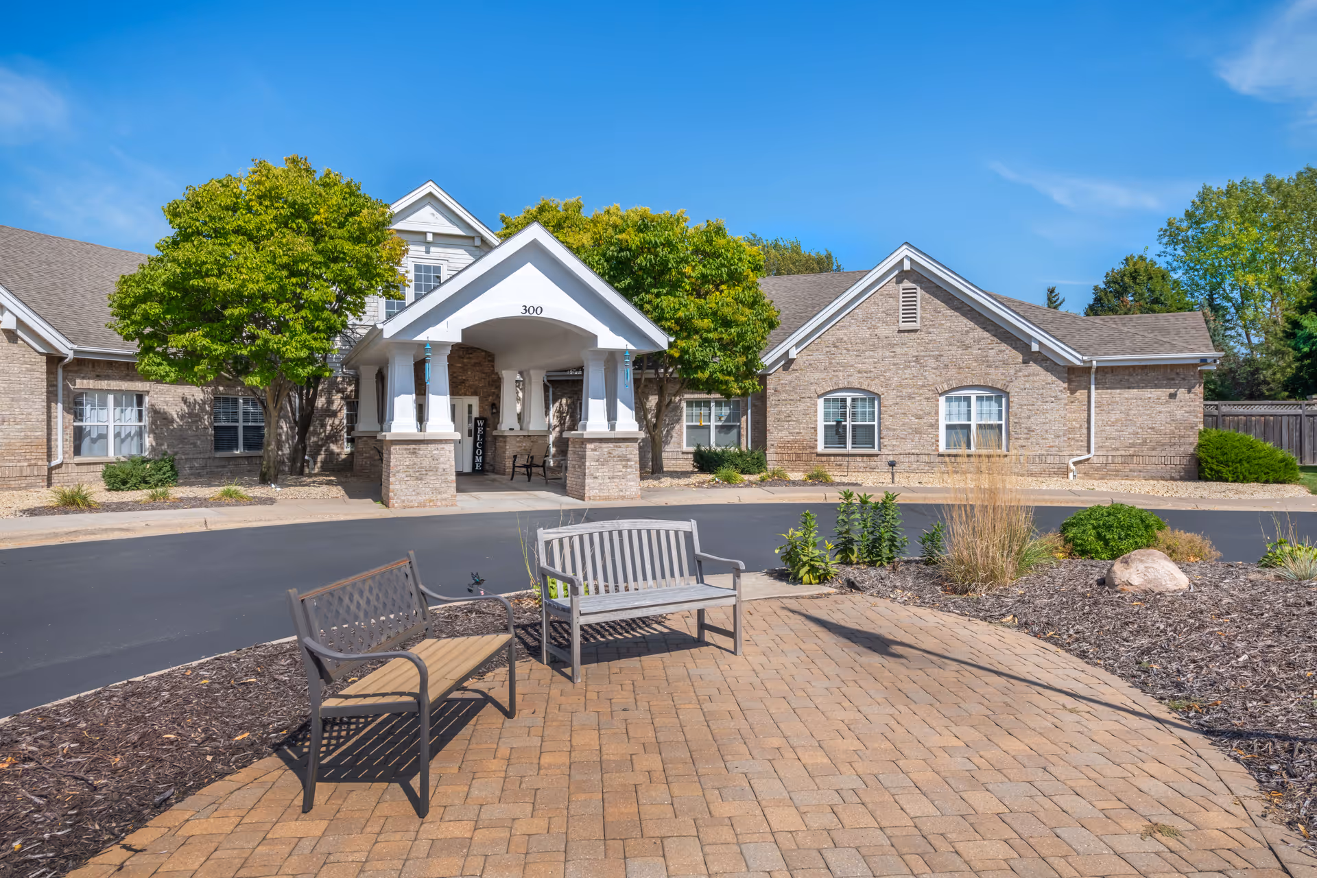 Exterior view of Brookdale North Oaks with brick building, trees, and outdoor benches.