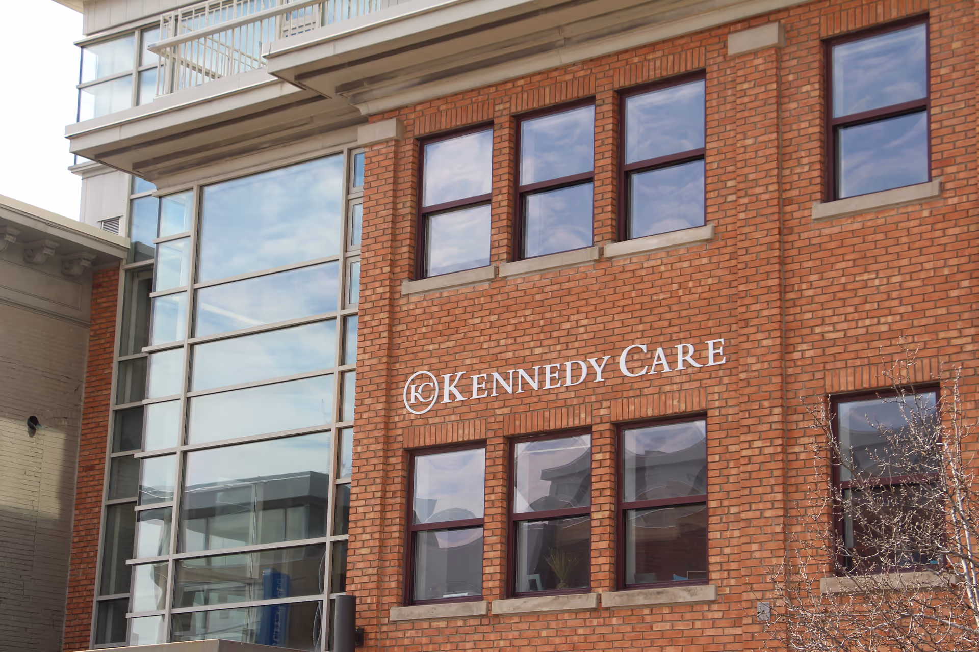 Brick building facade with Kennedy Care sign and large glass windows.