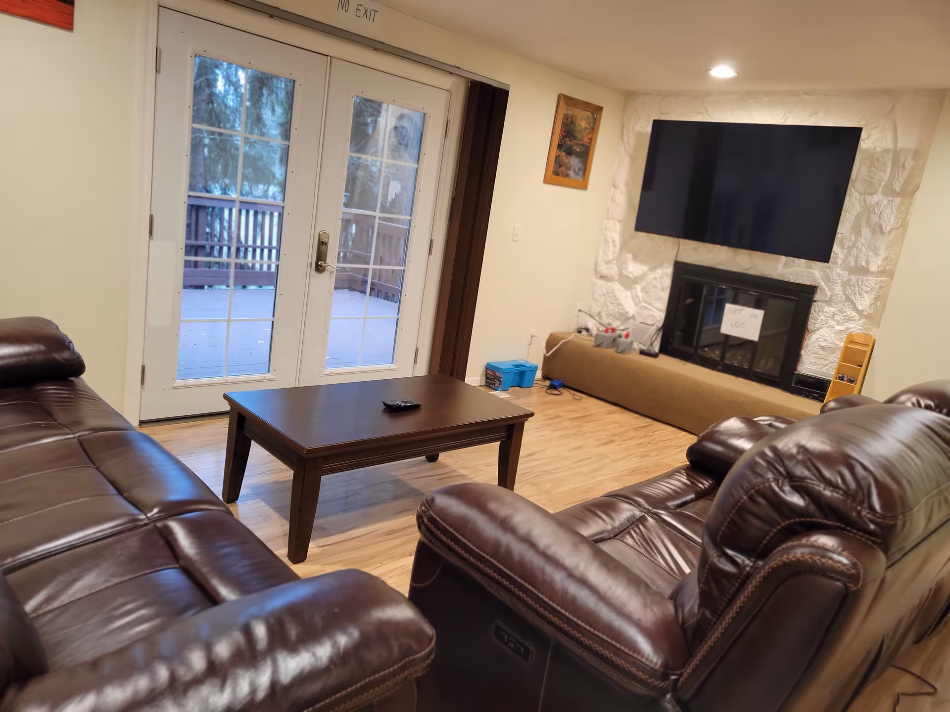 Cozy lounge area with brown leather sofas, coffee table, fireplace, and glass French doors.