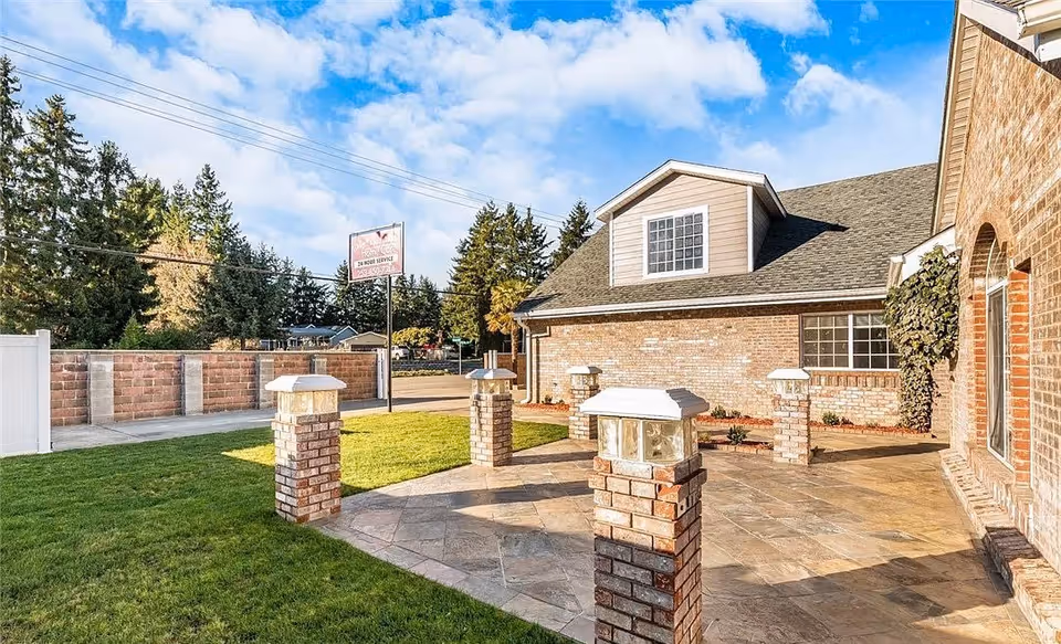 Exterior view of Valy's Adult Family Home: brick building, stone patio, green lawn.