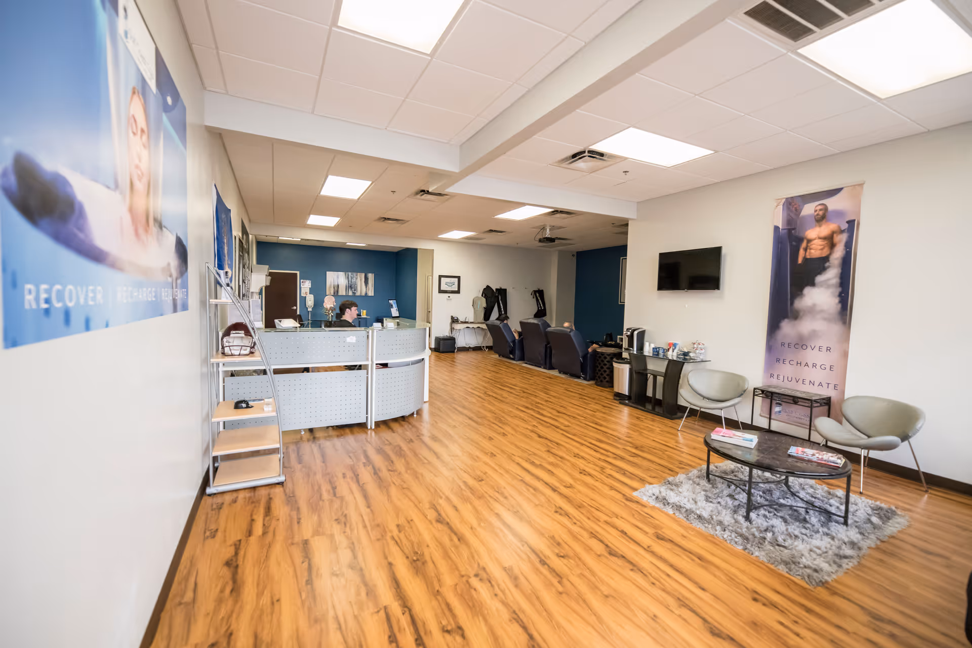 Spacious Saad Healthcare reception area with curved desk, seating, a wall TV, and posters.