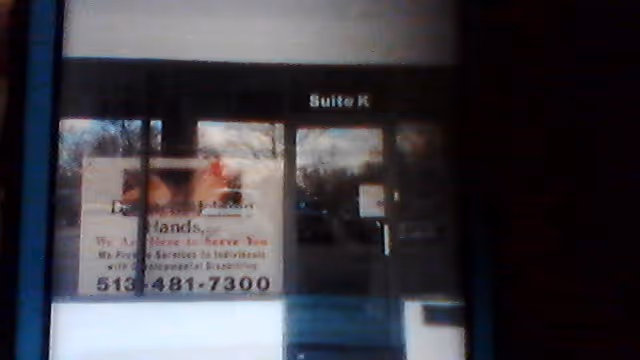 Glass entry door labeled Suite K with posters and signage in a dim storefront.