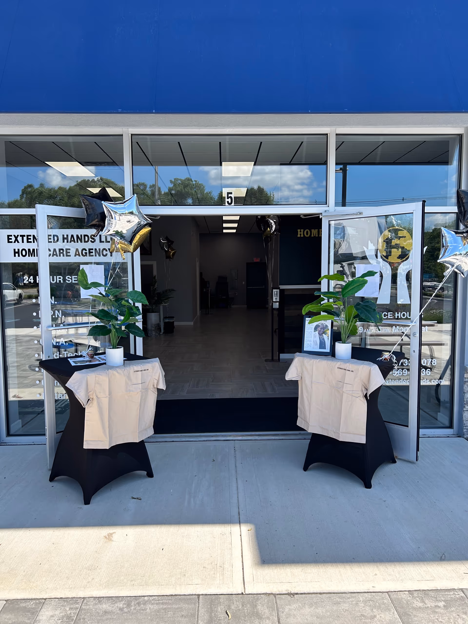 Open glass doors reveal Extended Hands Home Care Agency entrance with two decorated display tables
