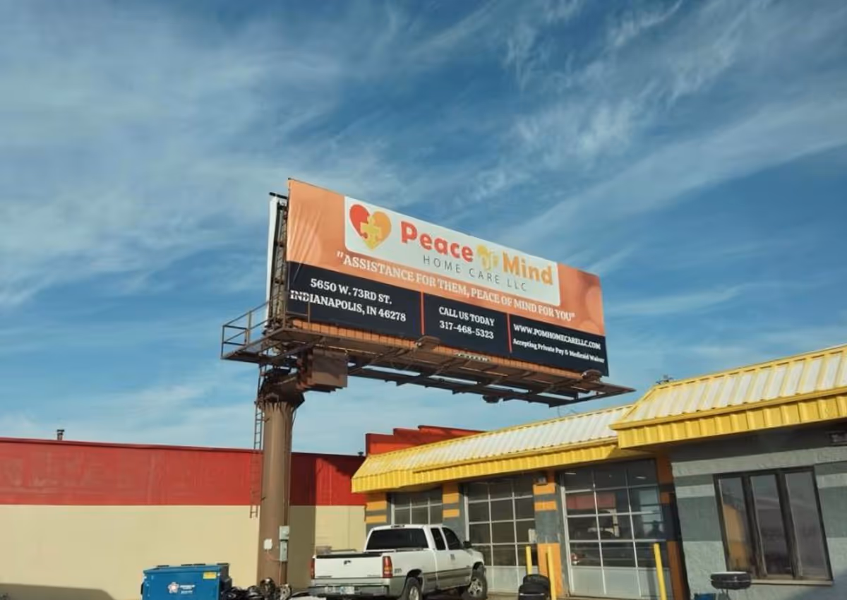 Billboard advertising Peace of Mind Home Care above a storefront with a yellow awning.