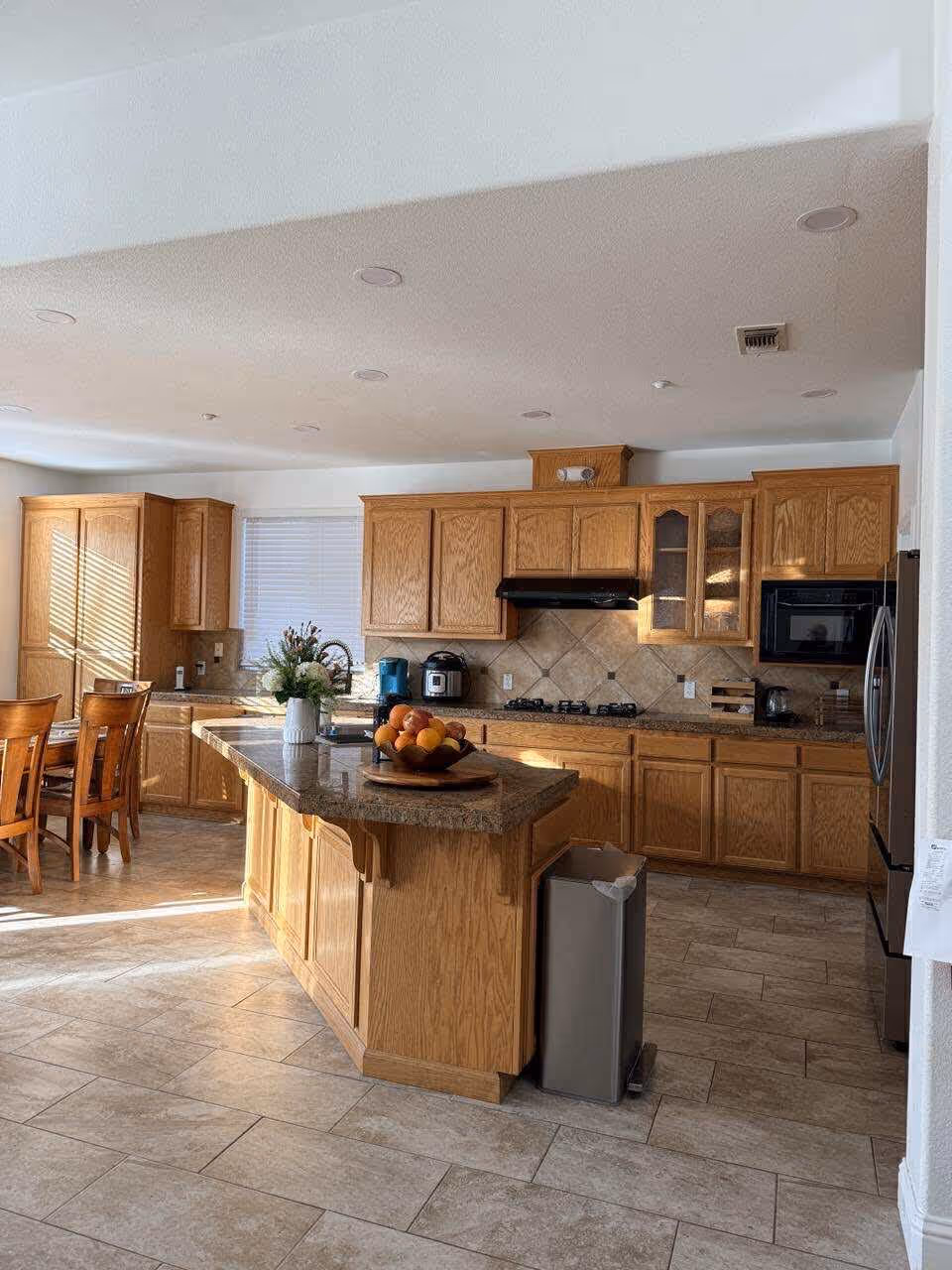 Open concept kitchen with wooden cabinets, island, and dining area.