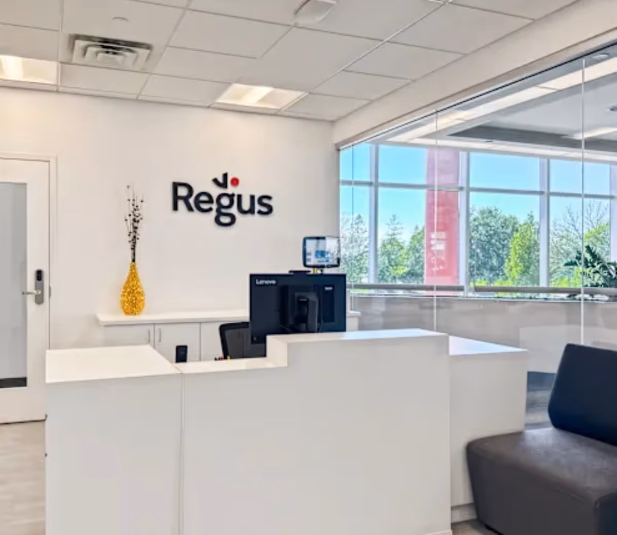 Bright reception area with white counters, computer, Regus sign, and large windows.