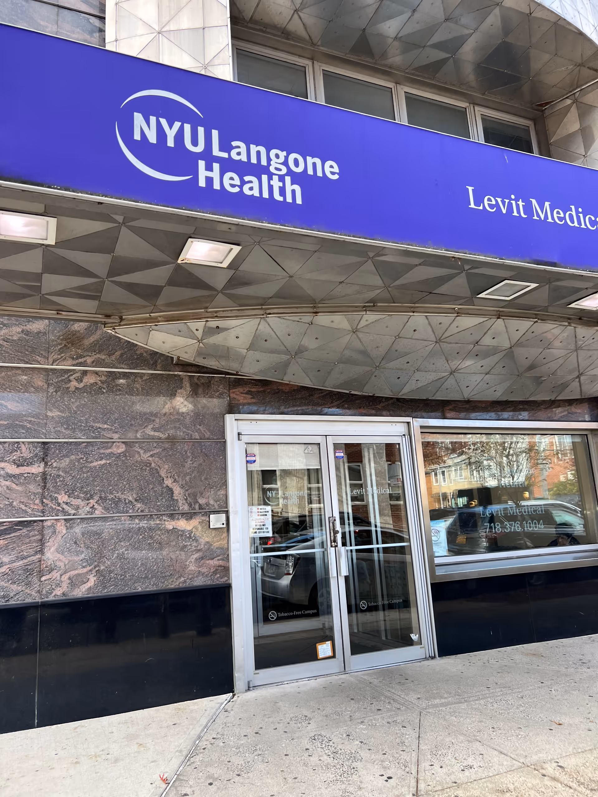 Blue NYU Langone Health Levit Medical sign above glass doors at a building entrance.