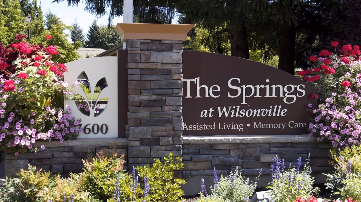 Exterior sign for The Springs at Wilsonville surrounded by colorful flowers.