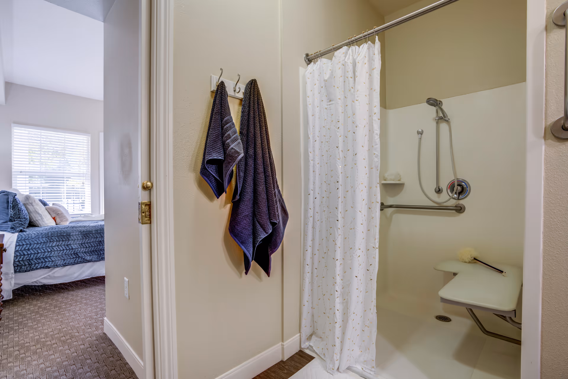 Shower area with curtain, wall towels, and a built-in shower chair.