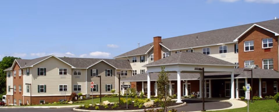 Exterior view of a senior living facility with a curved driveway and brick entrance.